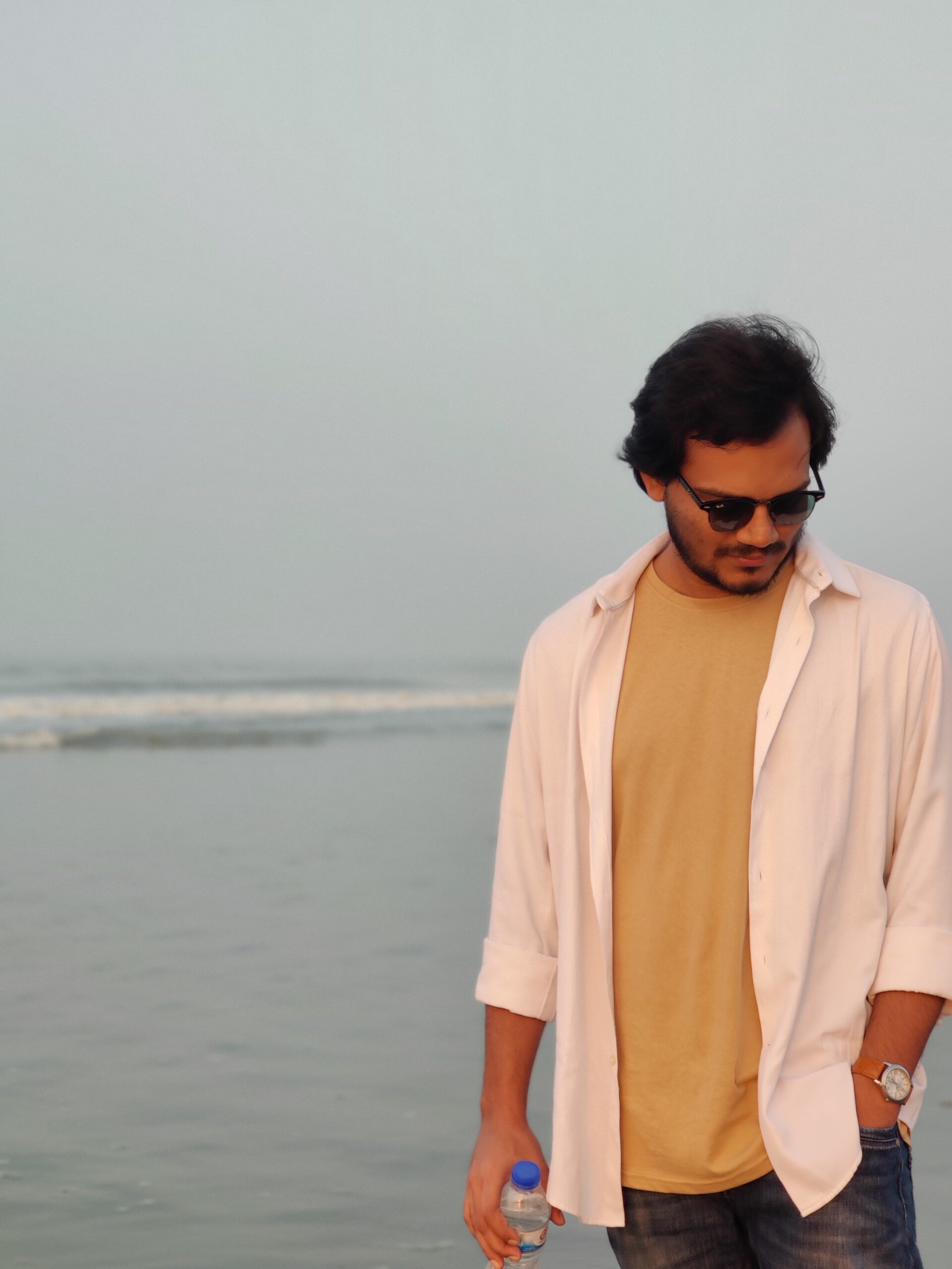 Shams Sumon is standing on a sea beach. 
